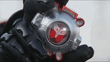 a person wearing black gloves is holding a clear object with a red logo on it