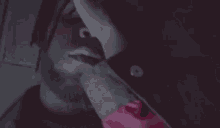 a man with dreadlocks is smoking a cigarette in a dark room with a knife in his hand .