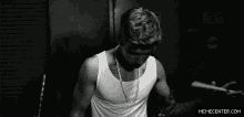 a black and white photo of justin bieber holding a drum stick and a drum stick in his hand .