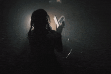 a woman in a dark room giving a peace sign with her hands