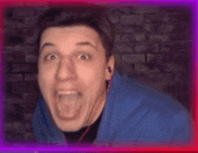 a man in a blue jacket is making a funny face with his mouth open in front of a brick wall .