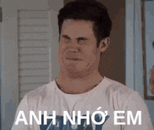 a man in a white t-shirt is making a funny face and says anh nho em .