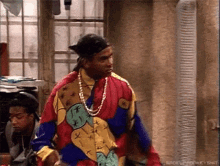 a man wearing a colorful shirt and a necklace is standing in a room .