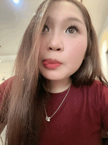 a woman wearing a red shirt and a necklace with a letter s on it