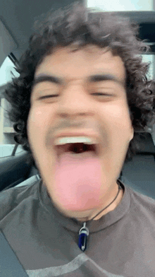 a man with curly hair sticking his tongue out