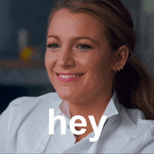 a woman in a white shirt is smiling with the word hey behind her