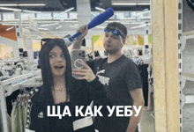 a man and a woman are taking a selfie in front of a mirror in a store with russian writing