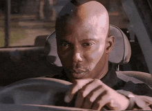 a bald man is sitting in the driver 's seat of his car