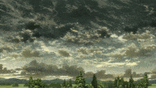 a cloudy sky over a field with trees and mountains in the background