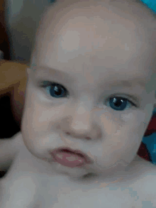 a close up of a baby 's face with blue eyes and red lips