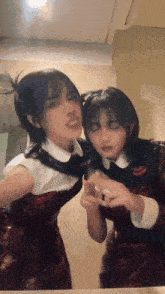 two girls are looking at each other in a mirror .