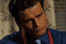 a man in a blue shirt and red tie is looking down .