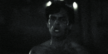 a black and white photo of a shirtless man looking at the camera
