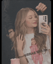 a woman is taking a picture of herself in a mirror wearing a shirt that says barbie