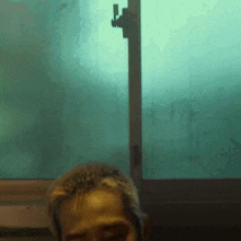 a man in a bathtub with a green window behind him