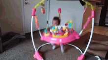 a baby is playing in a pink bouncer
