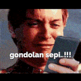 a man is crying while looking at a cell phone with the words gondolan sepi written on it .