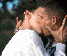 a man wearing a ring on his finger kisses another man on the cheek