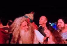 a man with long hair and a beard is dancing with a woman in a crowd of people .