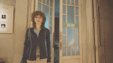 a woman stands in front of a door that has a green sign on it that says salida
