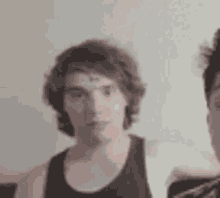 a man with a bandage on his forehead is standing next to another man in a black tank top .