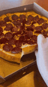 a person taking a slice of pepperoni pizza out of a cardboard box