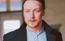 a man with a beard and blue eyes is wearing a suit and striped shirt