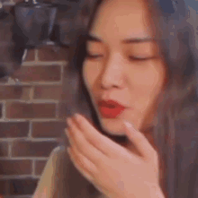 a woman with red lipstick on her lips is blowing a kiss with her hand .