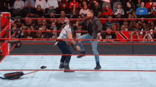 a wrestler is kicking another wrestler in the face during a match in a wrestling ring .