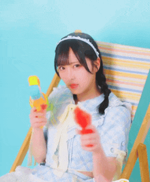 a girl in a blue dress is sitting in a chair holding a water gun