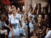 a woman in a blue dress is dancing in front of a crowd .
