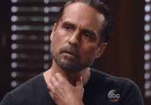 a man with a beard is sitting in front of a abc logo