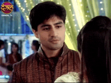 a man and a woman are looking at each other with a dangal tv logo in the background