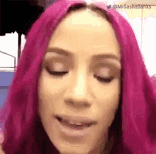 a woman with pink hair is making a funny face with her eyes closed .
