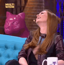 a woman sits on a blue couch with a pink cat in the background and the words multi show on the bottom right
