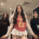 a woman in a pink shirt and white skirt is dancing in a room with two other women .