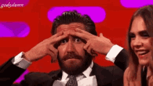 a man in a suit and tie is scratching his forehead with his fingers .
