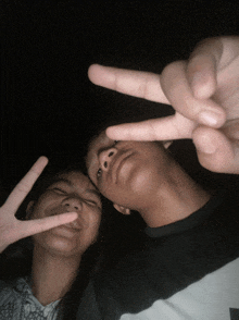 a boy and a girl are making peace signs with their hands