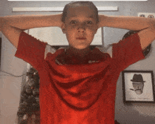 a boy wearing a red shirt with a picture of a skull on the wall