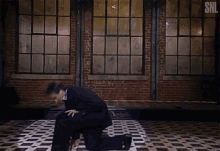 a man kneeling down in front of a brick wall with the snl logo
