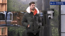 a man in a jacket stands in front of a camera that says 24h multicamara on it