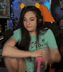 a woman wearing headphones and a t-shirt that says u9 prior is sitting in front of a rode microphone