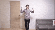 a man in a plaid shirt is standing in front of a door holding a remote control