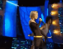 a woman is singing into a microphone on a stage in front of a crowd .