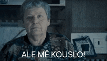an older woman is sitting in front of a stove with ale me kouslo written on the bottom