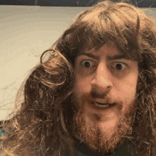 a man with long hair and a beard looks surprised