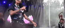 a woman is singing into a microphone on a stage while another woman is dancing behind her .