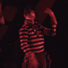 a man in a black and white striped shirt stands in the dark