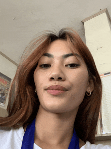a woman wearing a white shirt and a blue lanyard is taking a selfie