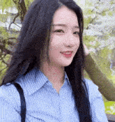 a young woman with long black hair is wearing a blue striped shirt and a backpack .